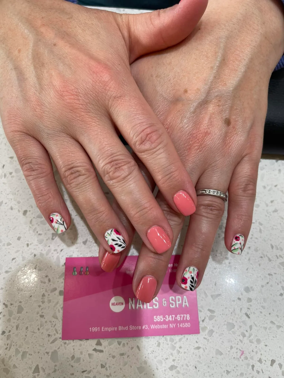 Coral gel nails with hand-painted flowers on the accent nails